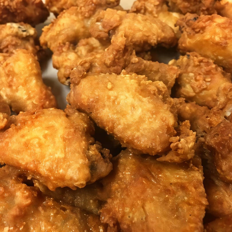 Close-up of golden-brown fried chicken wings, glistening with sauce, from Family Style Pizza.